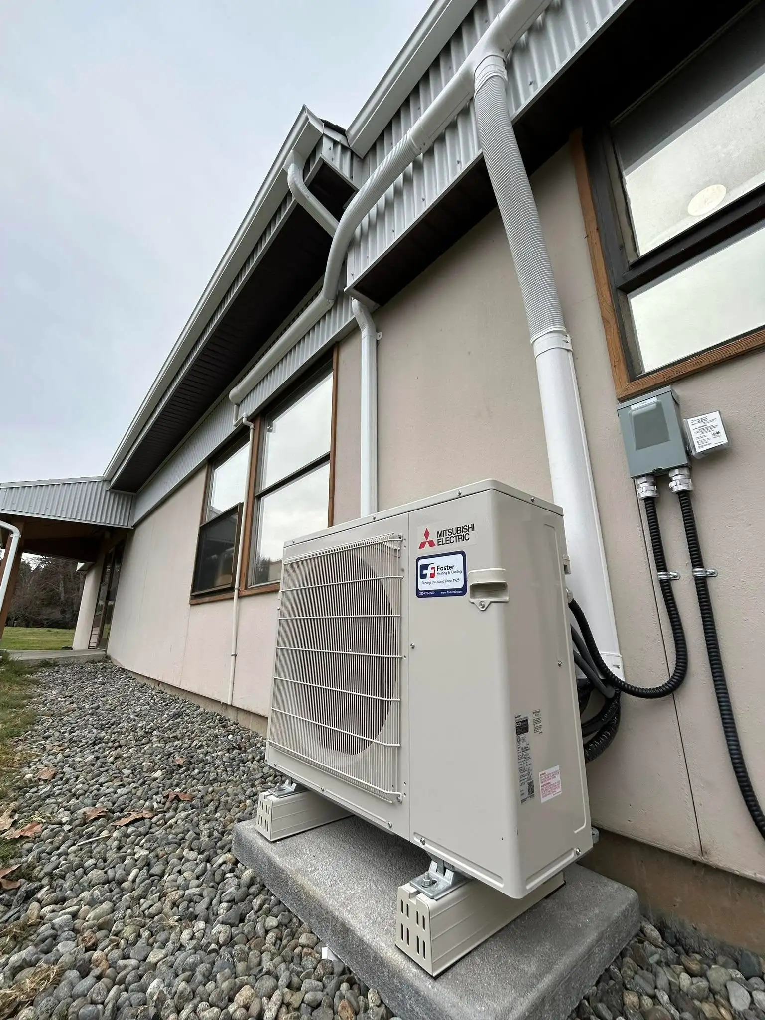 Mitsubishi Electric outdoor condenser unit with refrigerant lines running up modern home exterior