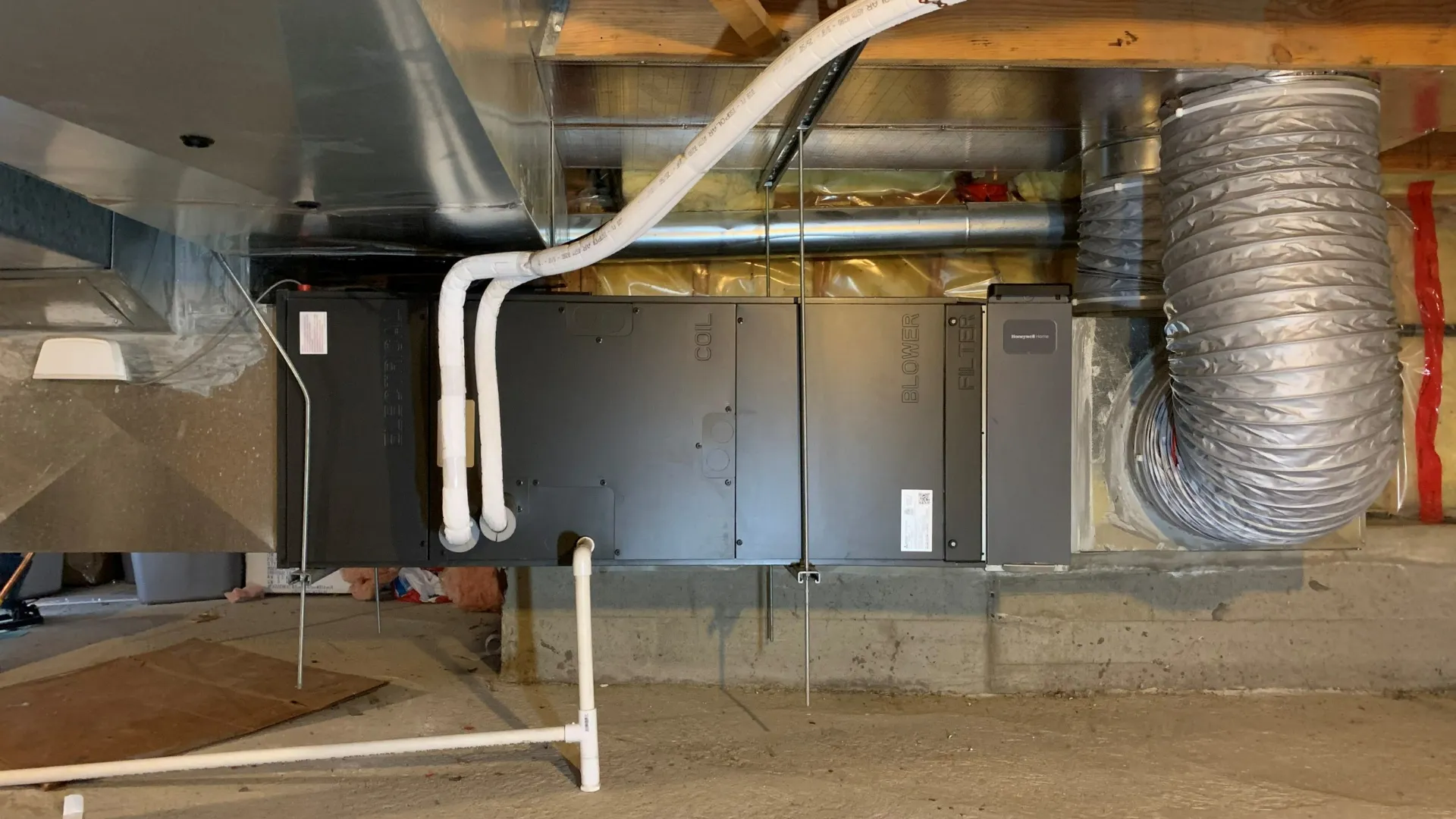HVAC air handler and ductwork installation in basement mechanical room with concrete foundation