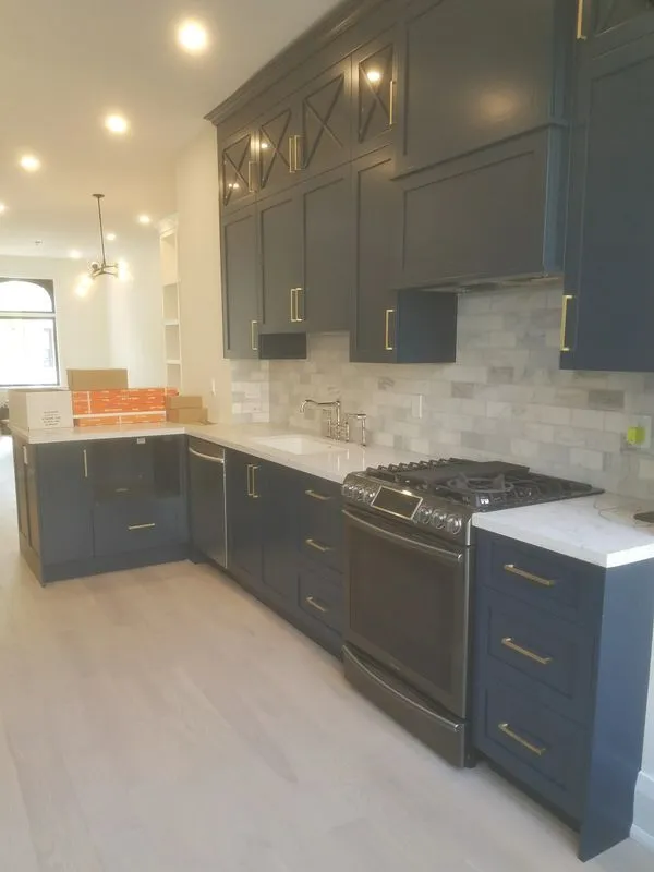 Dark navy kitchen cabinets with brass hardware, marble backsplash, and gas range during Toronto kitchen renovation