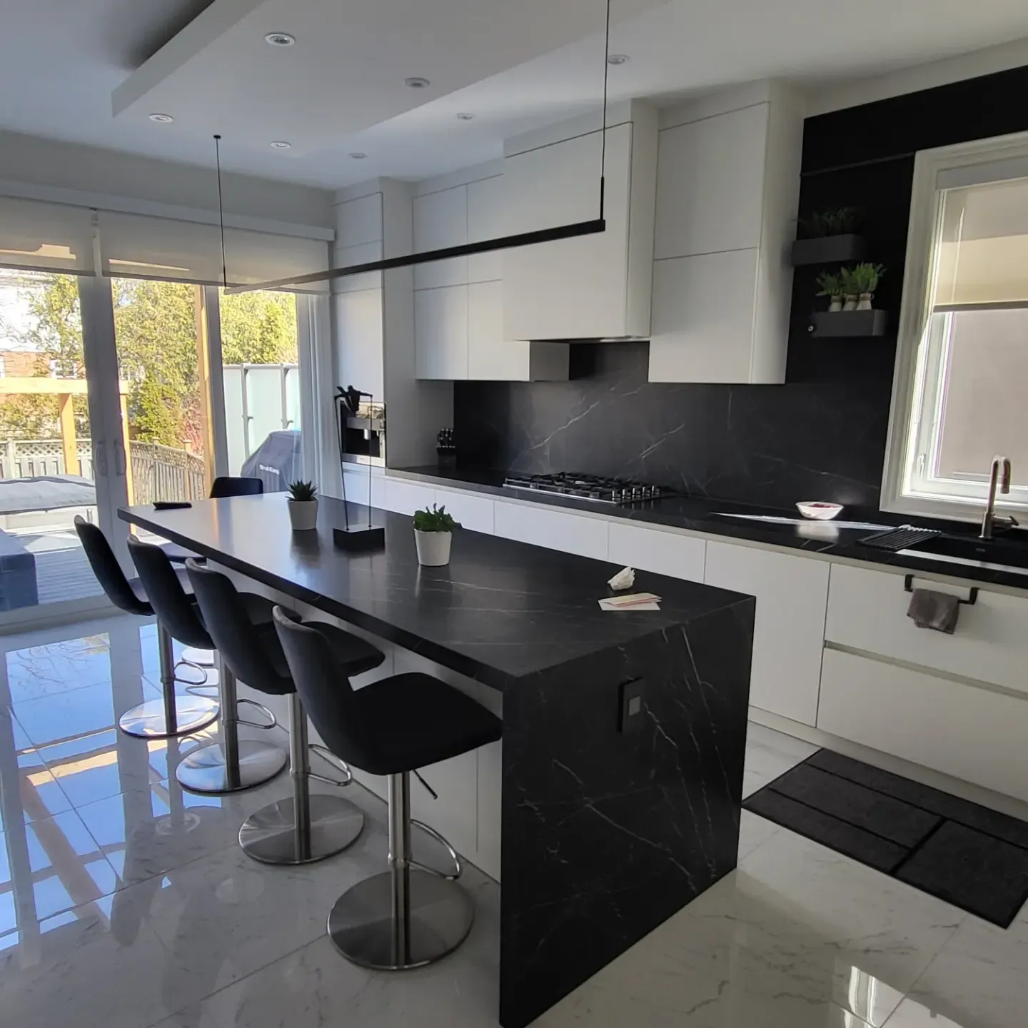 Renovated kitchen with black marble countertops, white cabinetry, large island seating, and backyard sliding door view