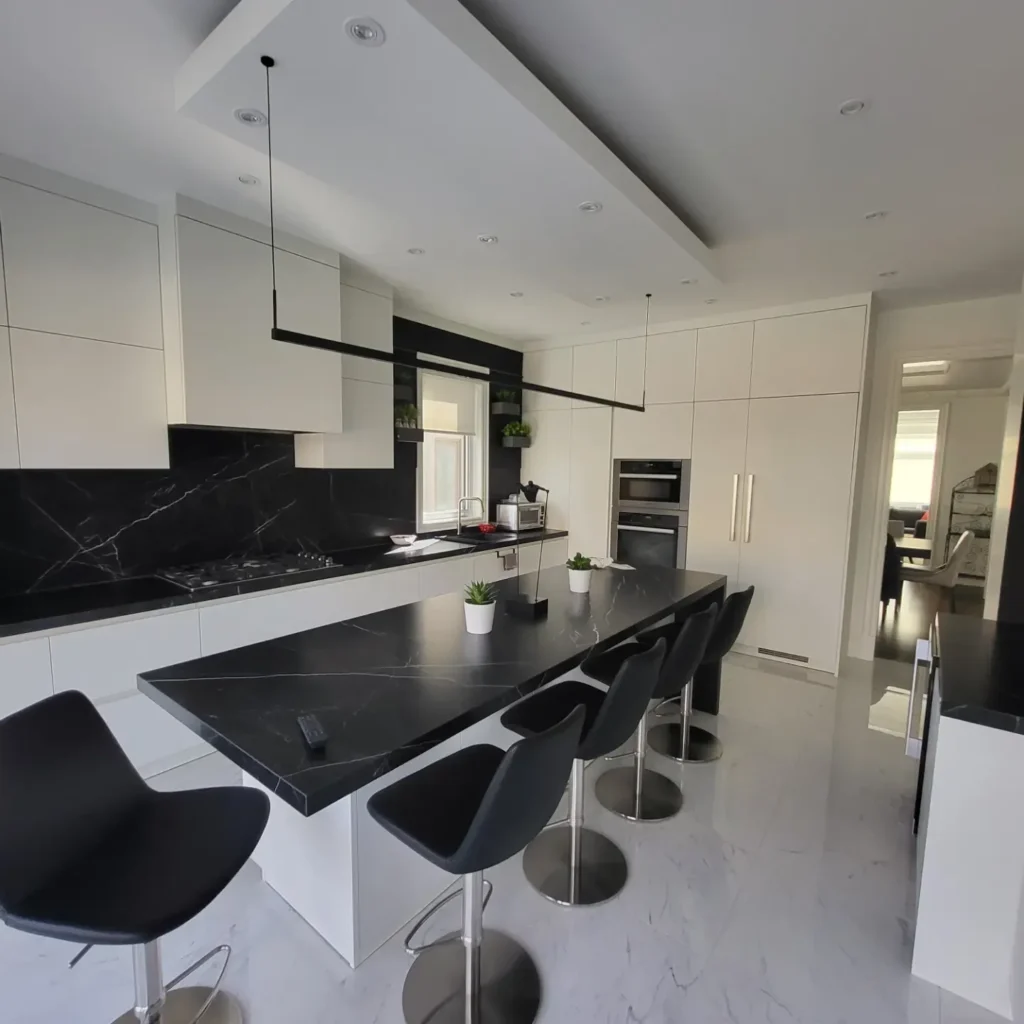 Modern kitchen with black marble island, white cabinetry, and bar stools in residential home